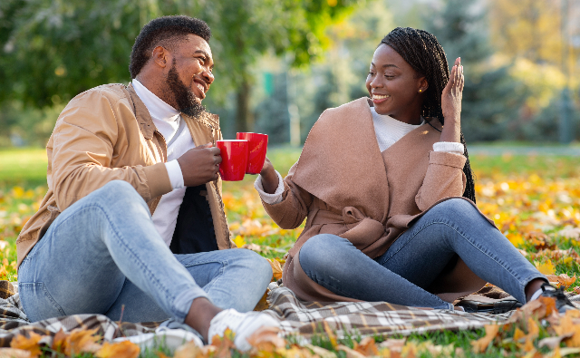 Black couple enjoying hot drink outside