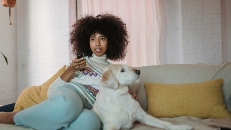 Black woman watching television with her dog sitting on her lap