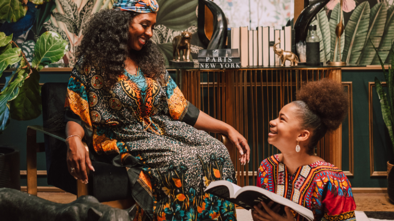 Black woman and young girl happily reading a book